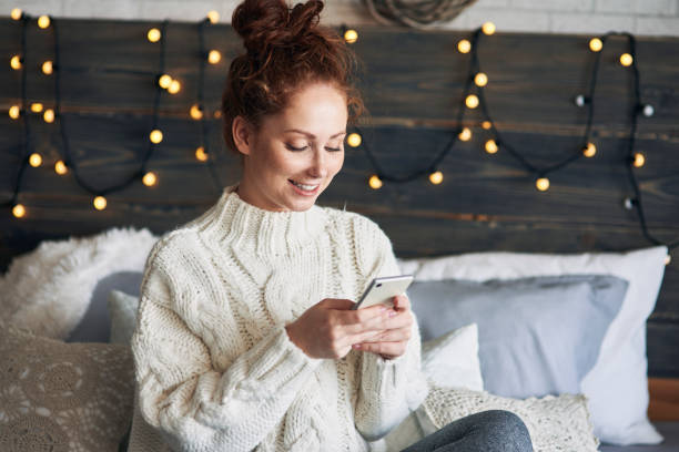 Jeune femme sur son lit avec une guirlande lumineuse en fond