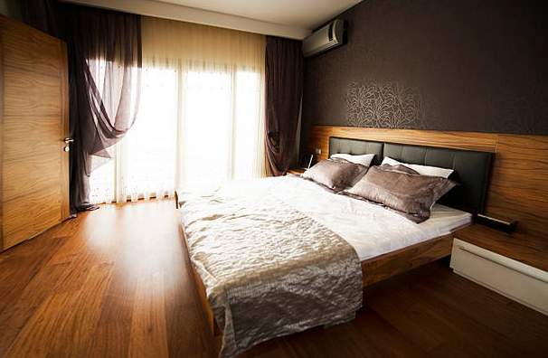 Chambre d'adulte avec parquet en bois sombre et murs marrons